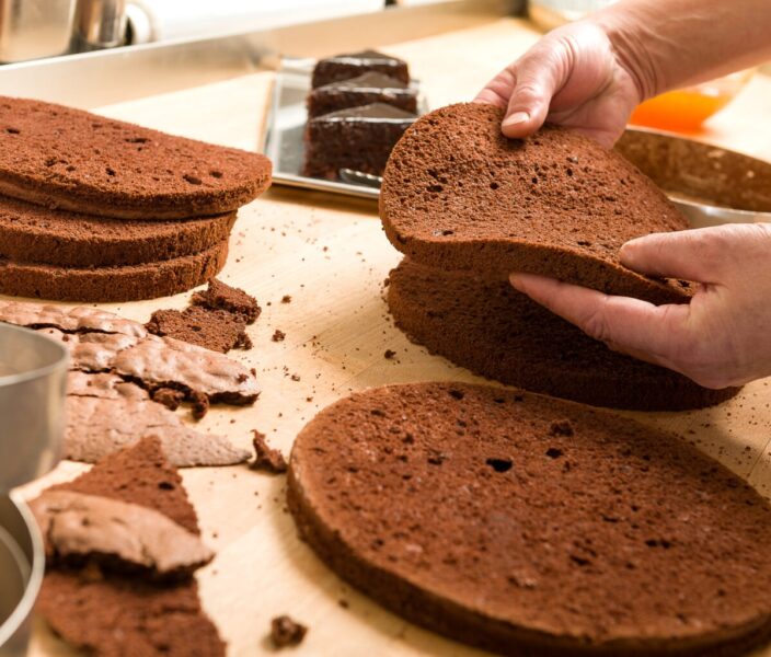 Chef cutting chocolate cake layers and stacking them